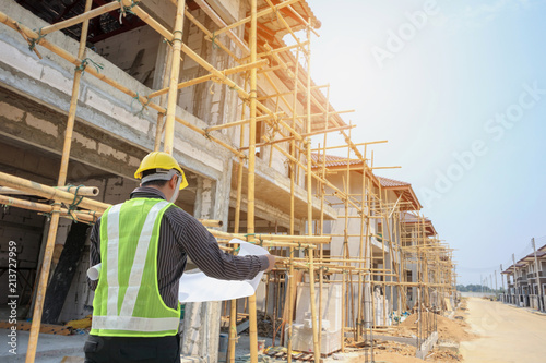 Professional engineer architect worker with protective helmet and blueprints paper at house building construction site