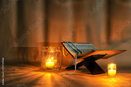 The Quran is placed on a wooden stand.Light candles. photo