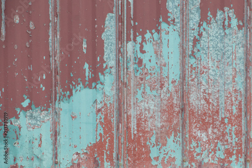 Grungy red metal painted sheet peeling paint © claire