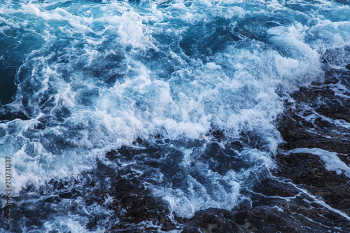 Fototapeta Naklejka Na Ścianę i Meble -  Dramatic foamy sea top view near the rocky shoreline