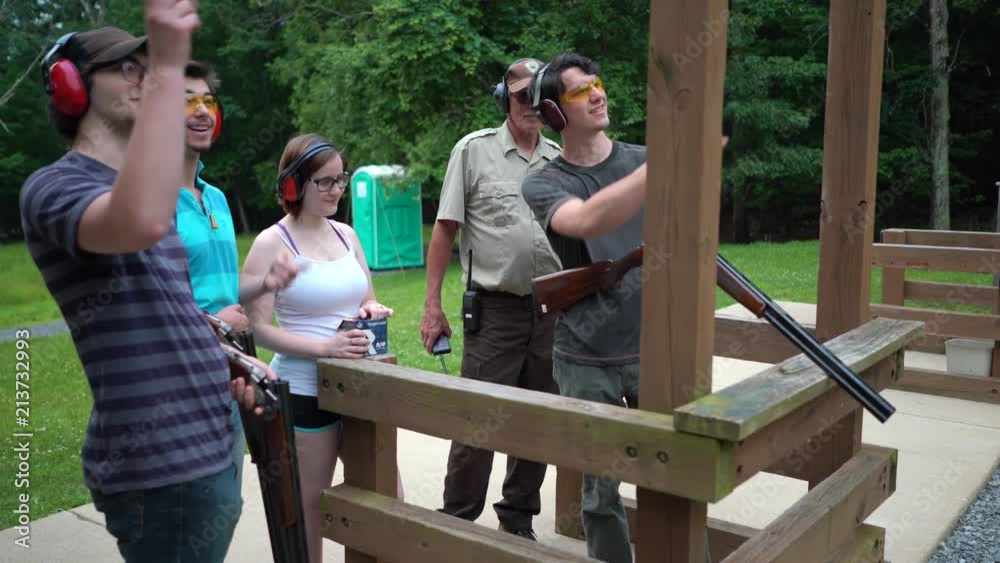 Steadicam of young men discussing how to shoot the wobble target and one young man holding the gun putting a cartridge in a chamber. Steadicam of young men discussing how to shoot the wobble target and one young man holding the gun putting a cartridge in a chamber.