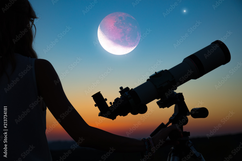 Obraz premium Girl looking at lunar eclipse through a telescope. My astronomy work.