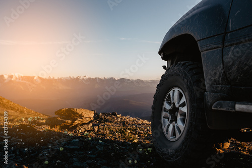 Big car wheel is standing on the rocks on mountain backdrop