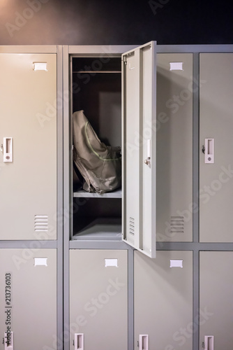 Grey and green sport bag sitting in locker room with opened door.