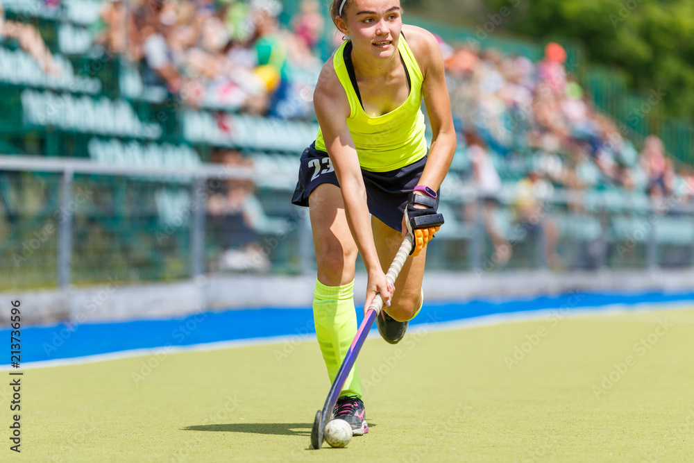 Young hockey player woman with ball in attack playing field hockey game