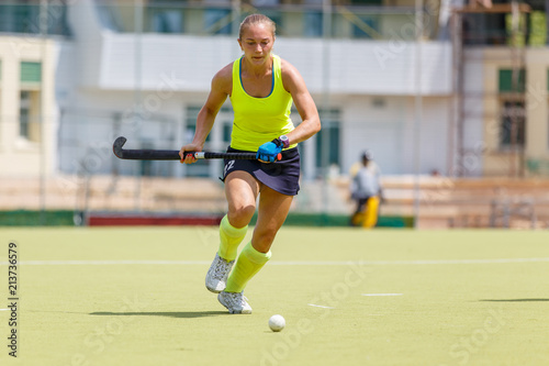 Young hockey player woman with ball in attack playing field hockey game