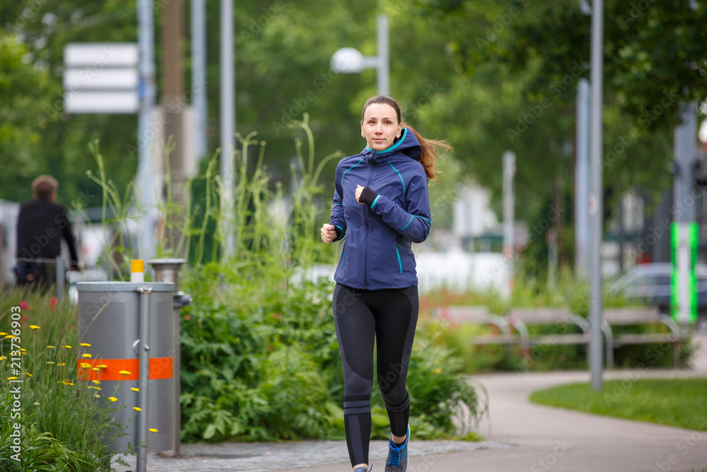 Young woman in blue jacket jogging in park. European girl running in the  morning. Image vith copy space Stock Photo | Adobe Stock