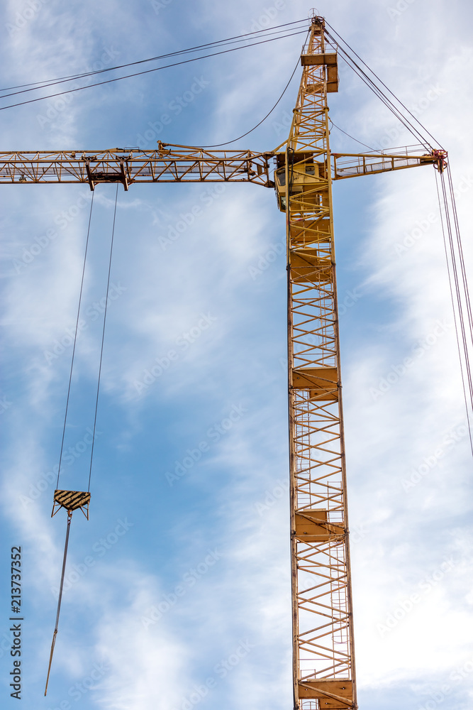 yellow tower crane on construction site against blue sky 