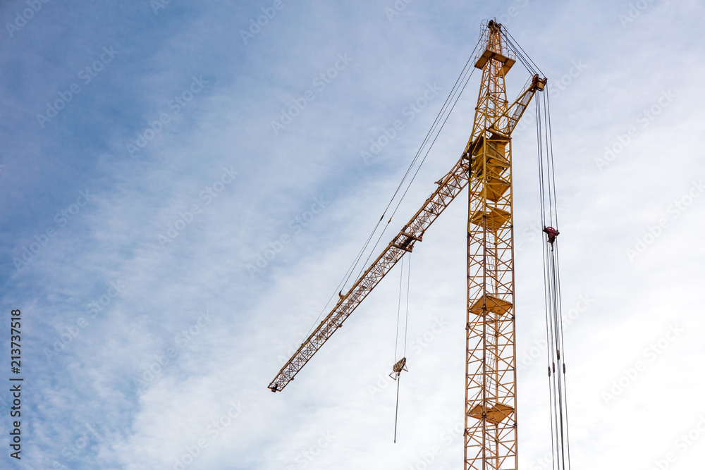 building construction site with yellow tower crane against blue sky