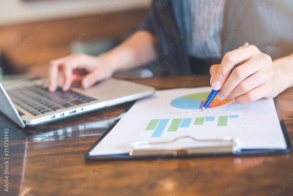Businessman working on analysis charts and graphs showing results.Her hand holds the pen and points to the graph.Business analysis and strategy.