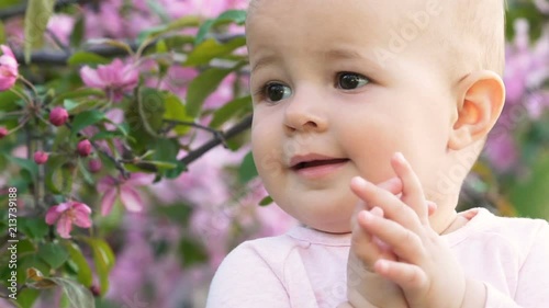 Sweety little happy cute cheerful funny playing and clap hand outside at green summer area slowmotion closeup. Looking for joy around, smiling, laugh and do applause bakground flower photo