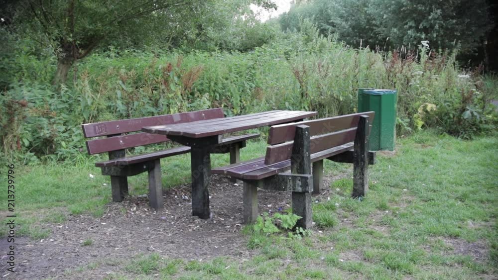 A Picknicbench with a Garbagebin next to it in Nature. A Picknicbench with a Garbagebin next to it in Nature.