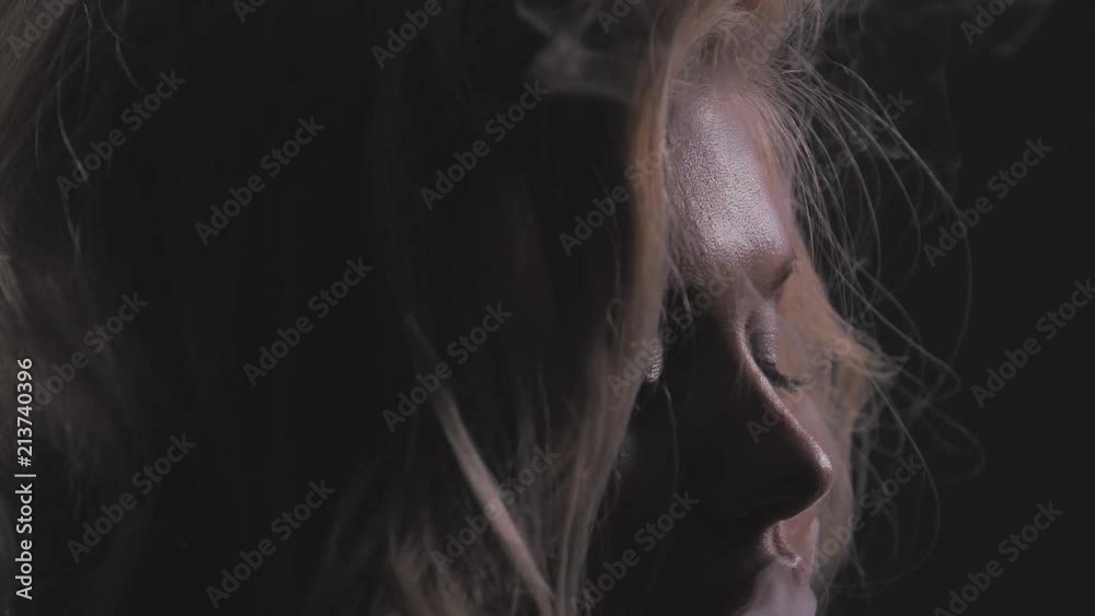 Attractive blonde girl in white thick smoke cloud, closeup portrait shot in slowmotion, dark background, 150fps Attractive blonde girl in white thick smoke cloud, closeup portrait shot in slowmotion, dark background, 150fps