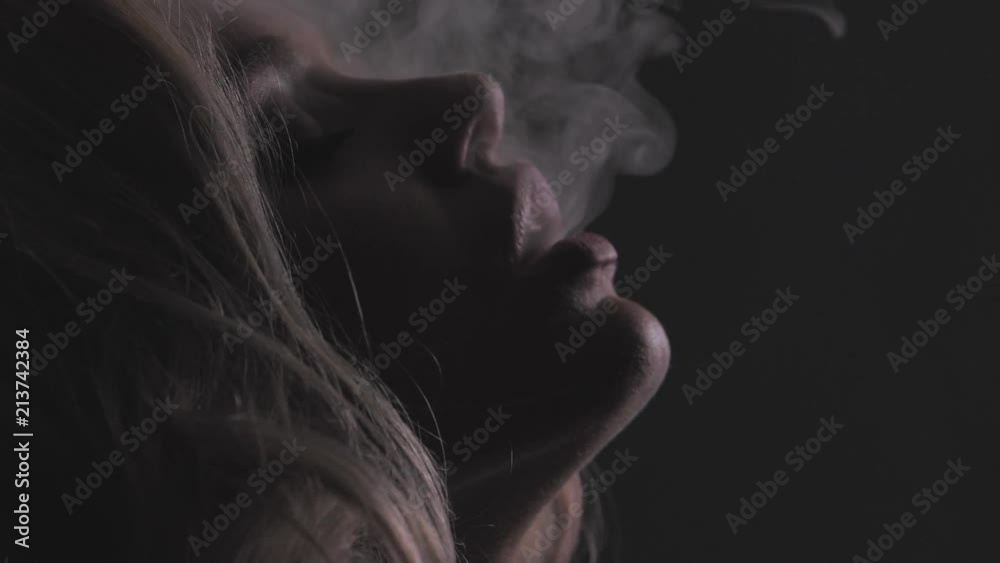 Attractive blonde girl in white thick smoke cloud, closeup portrait shot in slowmotion, dark background, 150fps Attractive blonde girl in white thick smoke cloud, closeup portrait shot in slowmotion, dark background, 150fps