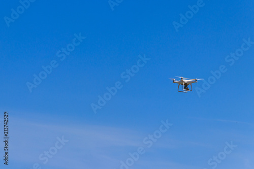 Drone with camera flying in blue sky