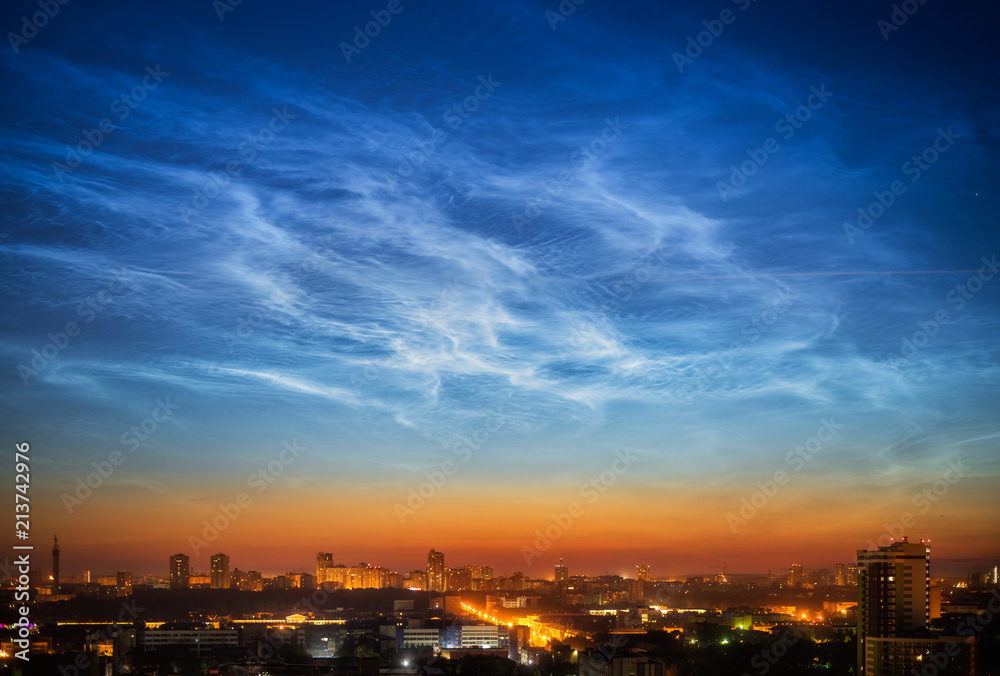 Noctilucent clouds over the city downtown at summer night