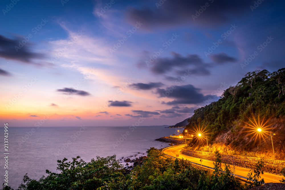 The seaside road adjacent to the mountain at sunset on the east side of Thailand.