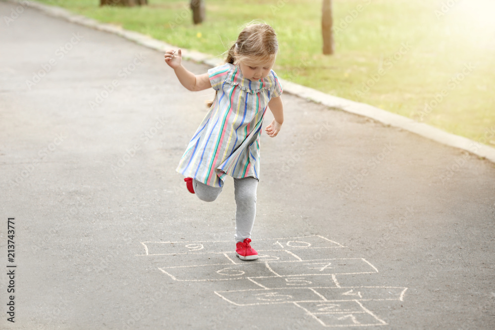 Cute little girl playing hopscotch, outdoors Cute little girl playing hopscotch, outdoors