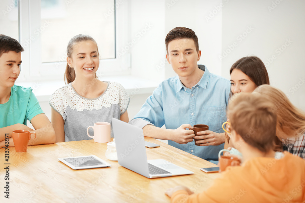 Group of cool teenagers with modern devices resting in cafe Group of cool teenagers with modern devices resting in cafe