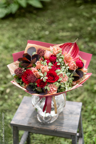 Beautiful red summer bouquet on wooden table. Arrangement with mix flowers. The concept of a flower shop. Content for the catalog photo