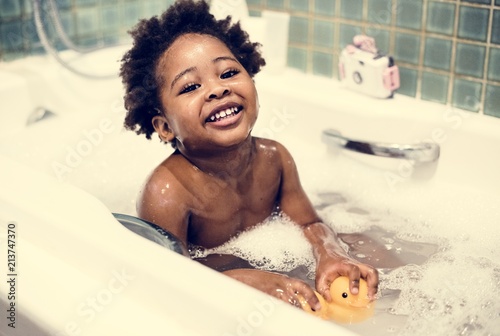 Tela African descent kid enjoying bath tub