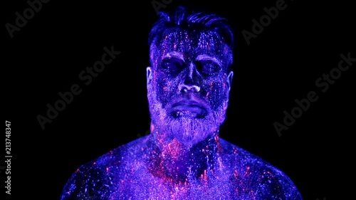 Concept. Portrait of a bearded man. The man is painted in ultraviolet powder photo