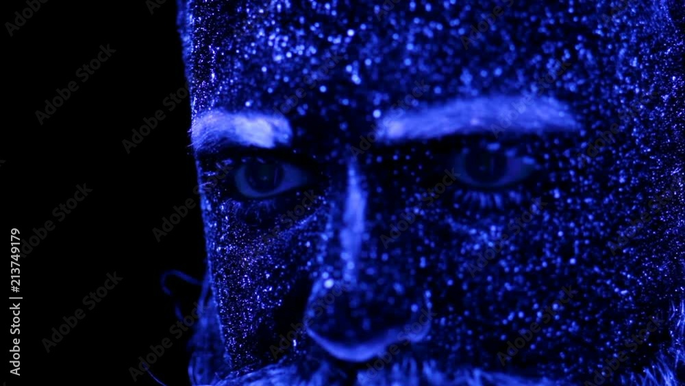 Concept. Portrait of a bearded man. The man is painted in ultraviolet powder Concept. Portrait of a bearded man. The man is painted in ultraviolet powder