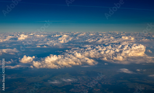 View from airplane window showing clouds and mountains in central europe.