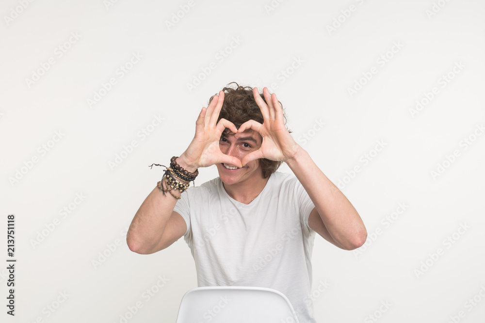 Portrait of happy handsome young man making heart with fingers on white background Portrait of happy handsome young man making heart with fingers on white background