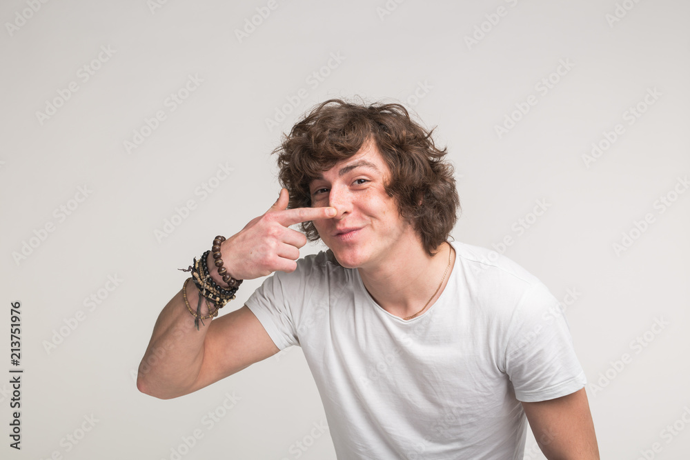 Portrait of funny young man pointing on his nose in white t-shirt Portrait of funny young man pointing on his nose in white t-shirt