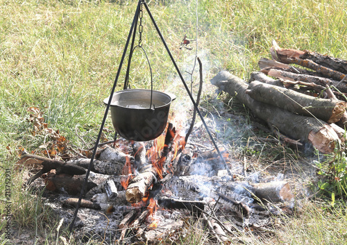 Cooking food in a kettle on a firewood fire at a picnic in summer in good clear weather