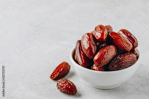 Dried dates in white bowl on grey background photo