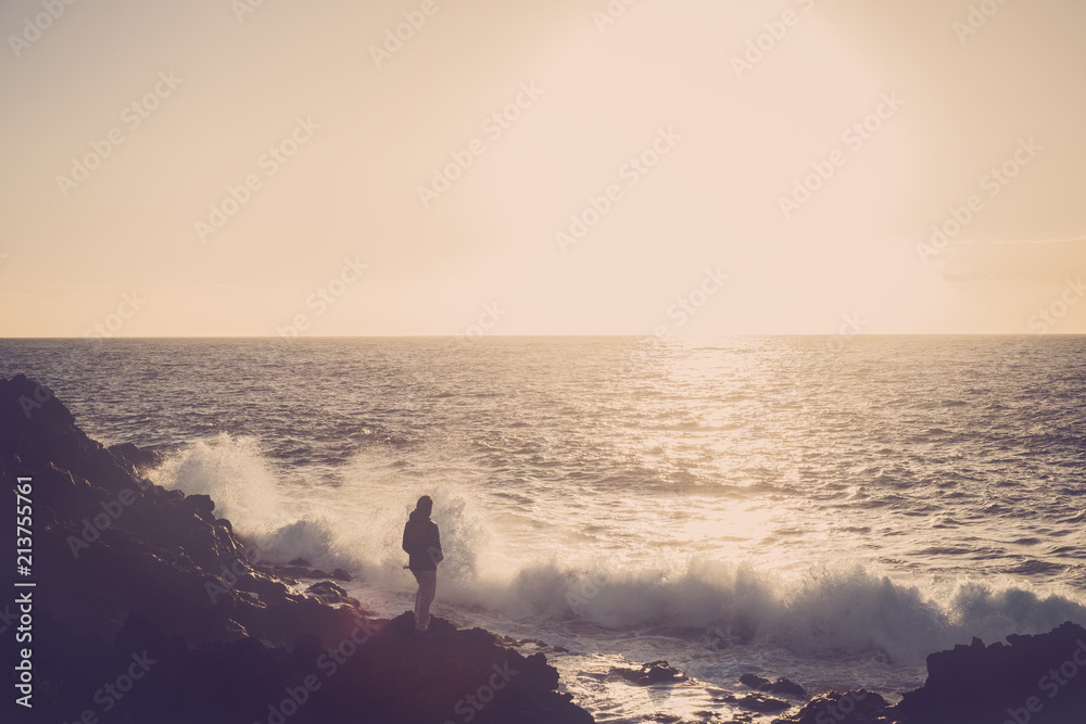 45-year-old man watches the sea and the waves at sunset, relaxing and reflecting about the life. travel and vacation concept. landscape with ocean and horizon and sunlight