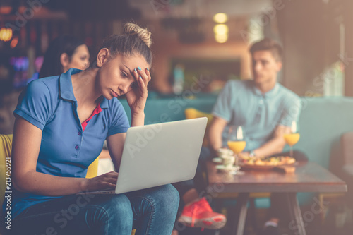 Young female student is using laptop computer in cafe