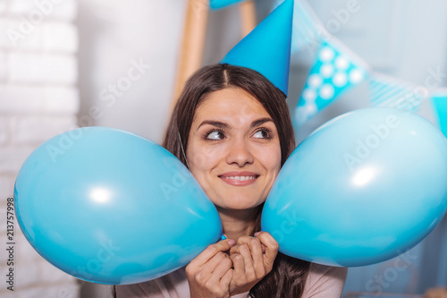 Happy woman. Charming brunette keeping smile on her face and holding balloons in both hands