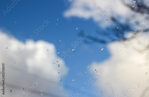 summer rain drops on glass blurred background blue sky white cloud