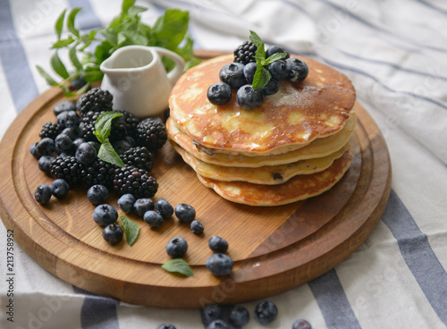 Pancakes with blackberries, blueberries and mint on the kitchen board - top view