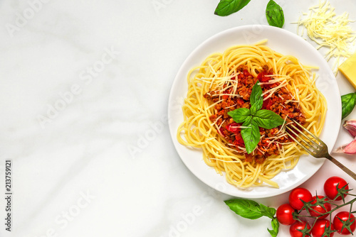 Spaghetti bolognese on a white plate with fork on white marble table. healthy food. top view