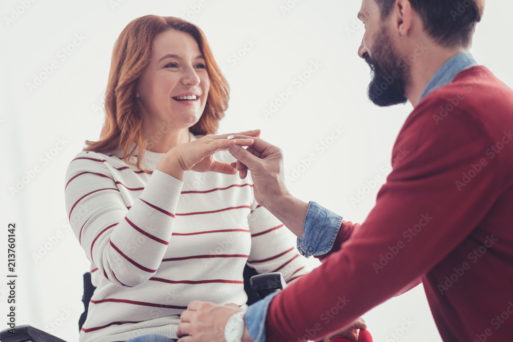 Important step. Cheerful young man asking his beautiful girlfriend to marry him and looking at her while giving the ring Important step. Cheerful young man asking his beautiful girlfriend to marry him and looking at her while giving the ring