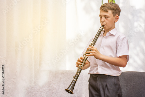 Fotografering The boy learns to play the clarinet at the window