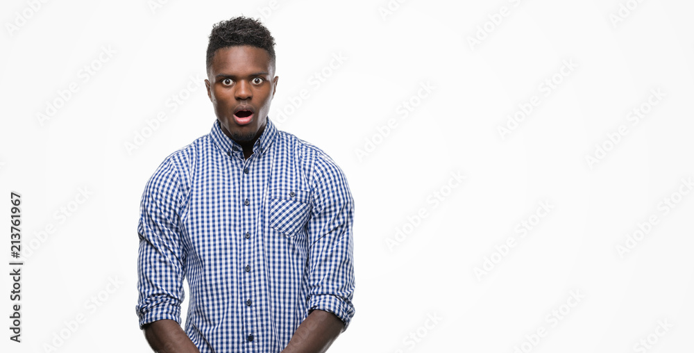 Young african american man wearing blue shirt afraid and shocked with surprise expression, fear and excited face.