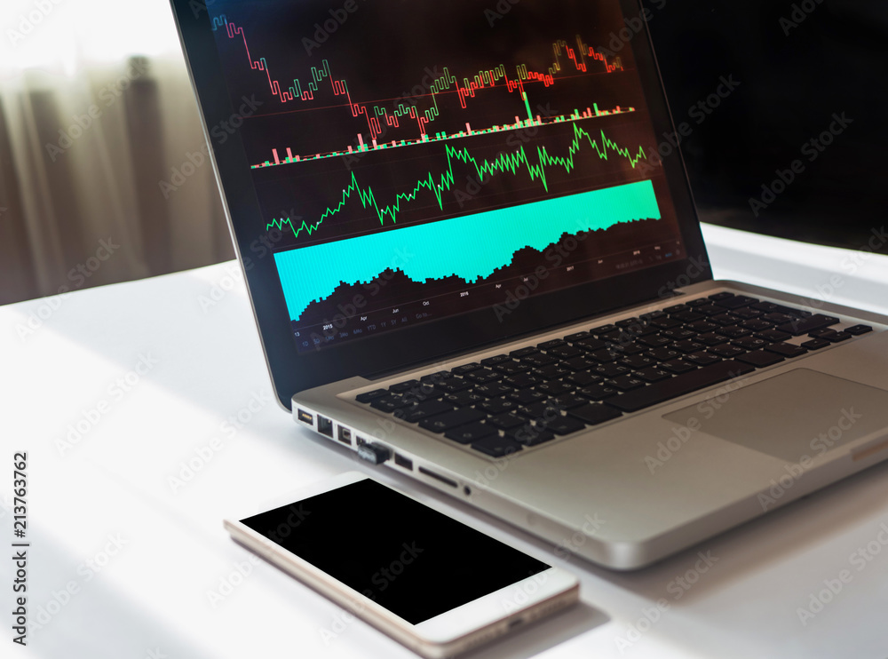 Phone and laptop with business and financial graph on the screen. Copy space on smartphone Phone and laptop with business and financial graph on the screen. Copy space on smartphone