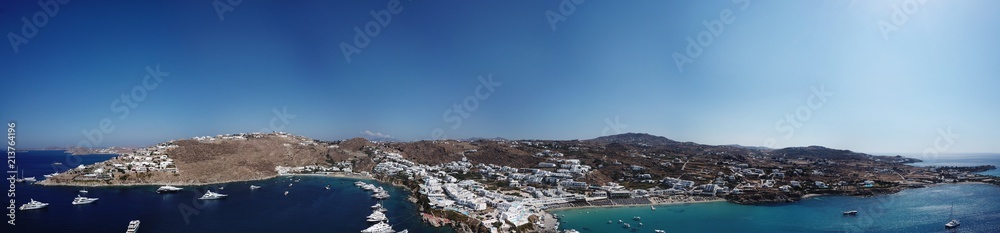 Aerial ultra wide panoramic drone view of iconic turquoise clear water beach of Psarou and Platy Yalos with yachts docked, Mykonos island, Cyclades, Aegean, Greece