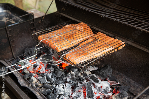 Salmon steak preparing on a barbecue grill over charcoal. Outdoor.
