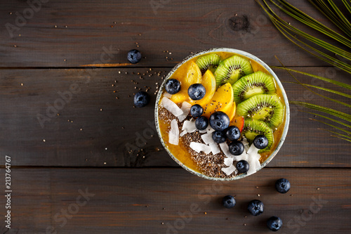 Peach smoothie bowl with kiwi fruit, chia seeds and coconut chips. Food photography with copy space.