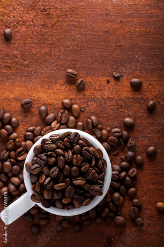  Photo closeup of coffee beans in white cup. Rusty background. Copy space.