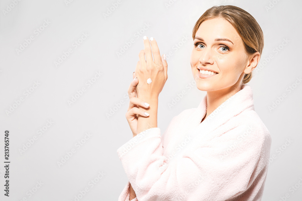 Young pretty smiling woman wearing hand cream on her perfect smooth hands. Face portrait on isolated white background. Young pretty smiling woman wearing hand cream on her perfect smooth hands. Face portrait on isolated white background.