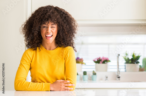 African american woman wearing yellow sweater at kitchen winking looking at the camera with sexy expression, cheerful and happy face.