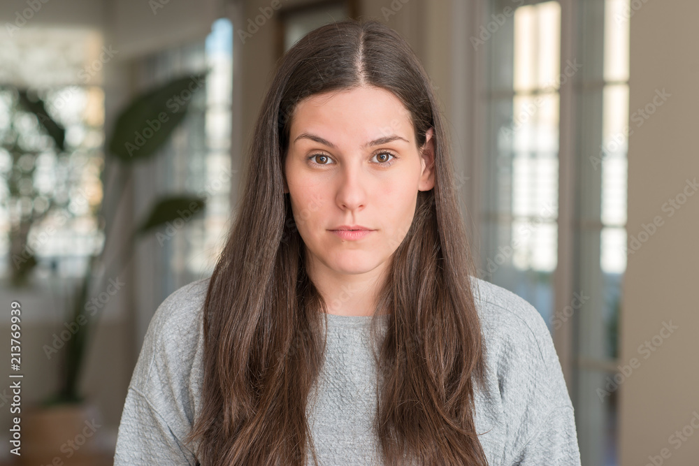 Young beautiful woman at home with serious expression on face. Simple and natural looking at the camera. Young beautiful woman at home with serious expression on face. Simple and natural looking at the camera.
