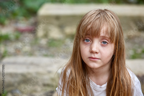 Portrait of sad vulnerable little girl in dirty alley, shallow depth of field.